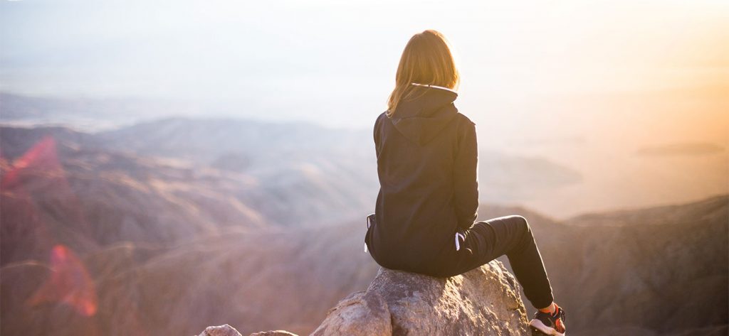lady sitting on top of mountain looking out: positive visualisation